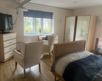 Twin room with two armchairs and a TV. View of the gardens from the bedroom.